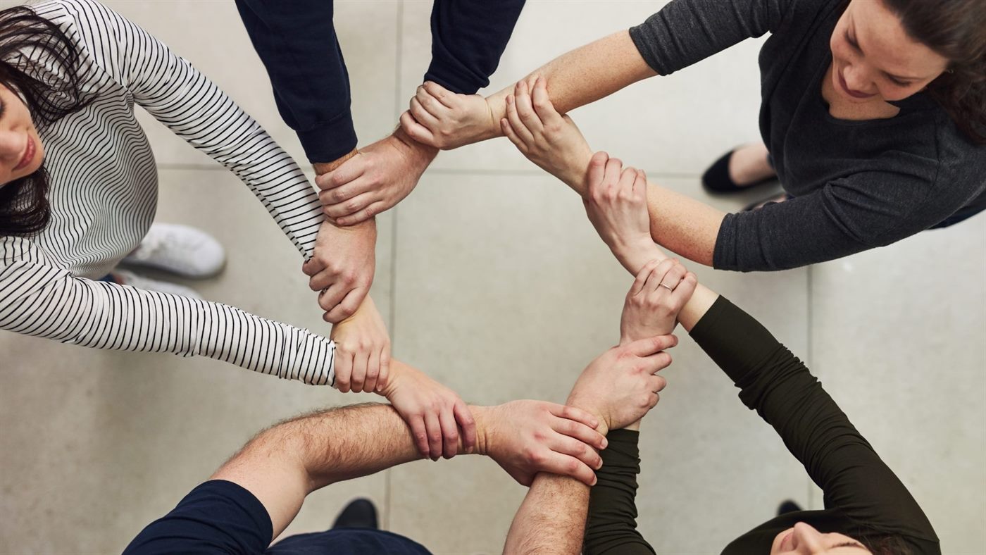 Many hands joined together in the centre of a circle